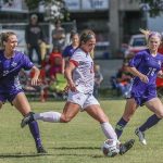 A female nursing student is pictured playing soccer, wearing a Crescent City Classic lanyard.