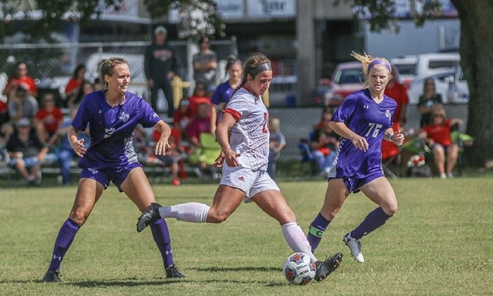 A female nursing student is pictured playing soccer, wearing a Crescent City Classic lanyard.